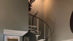 A modern interior with a spiral staircase, a beige sofa with a decorative pillow, and a framed artwork on the wall. - 8/27- 9/4  open  5 STARS  Great ratings- Hidden Gem Great Lagoon/Golf/pool view (Hilton Head Island)