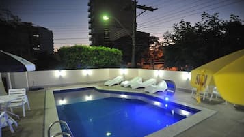 Una piscina al aire libre, sombrillas, sillones reclinables de piscina