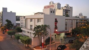 Un hotel llamado 'PLENOTEL' con un estilo arquitectónico moderno, que cuenta con una entrada destacada y una escalera que conduce a los pisos superiores.