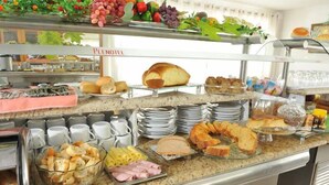 Una barra de buffet con diversos alimentos, como pan, bollería y una variedad de quesos.