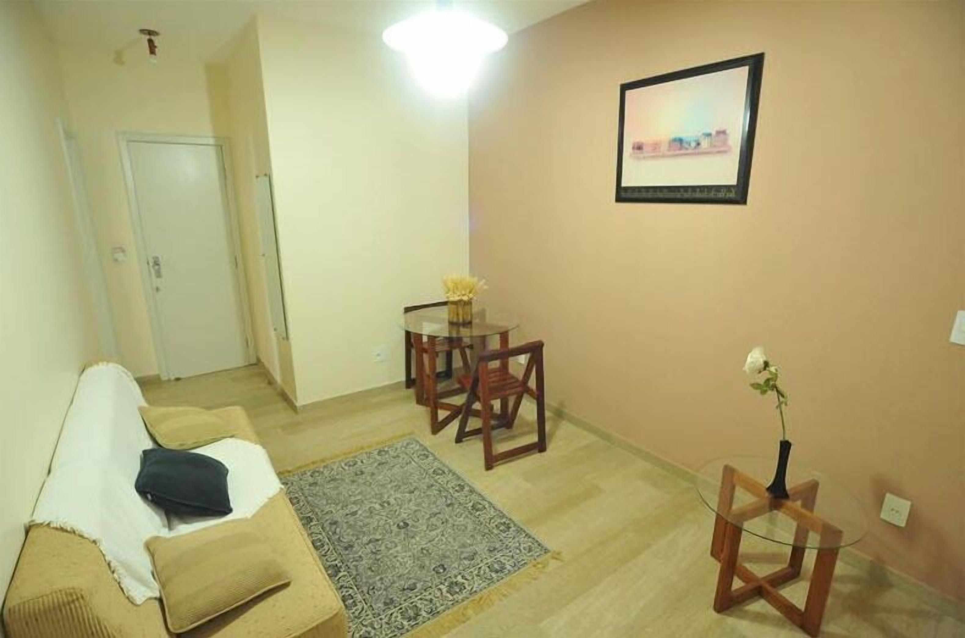A living room with a sofa, a small table with a vase, a rug, and a framed picture on the wall.