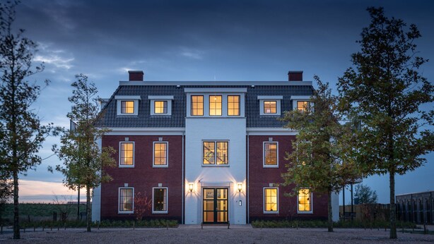 A large, two-story house with a symmetrical facade, multiple windows, and a central entrance.