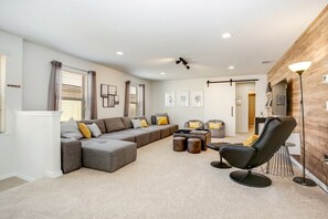 A modern living room with a sectional sofa, a black armchair, and a coffee table.