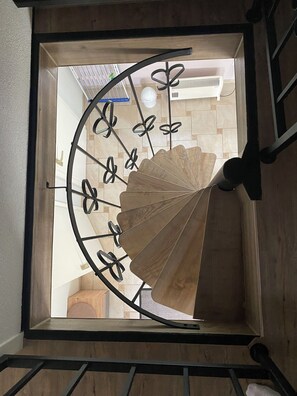 Un escalier en colimaçon avec des marches en bois et une rampe en métal.