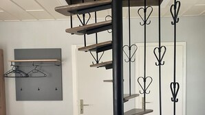 Eine Wendeltreppe mit Holzhäuschen und Metallgeländern in einem Raum mit Fliesenboden und einer Tür im Hintergrund.