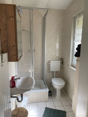 Une salle de bain avec une douche, des toilettes, un lavabo et une fenêtre.