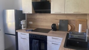 Eine kleine Küche mit Kühlschrank, Herd und Spüle.