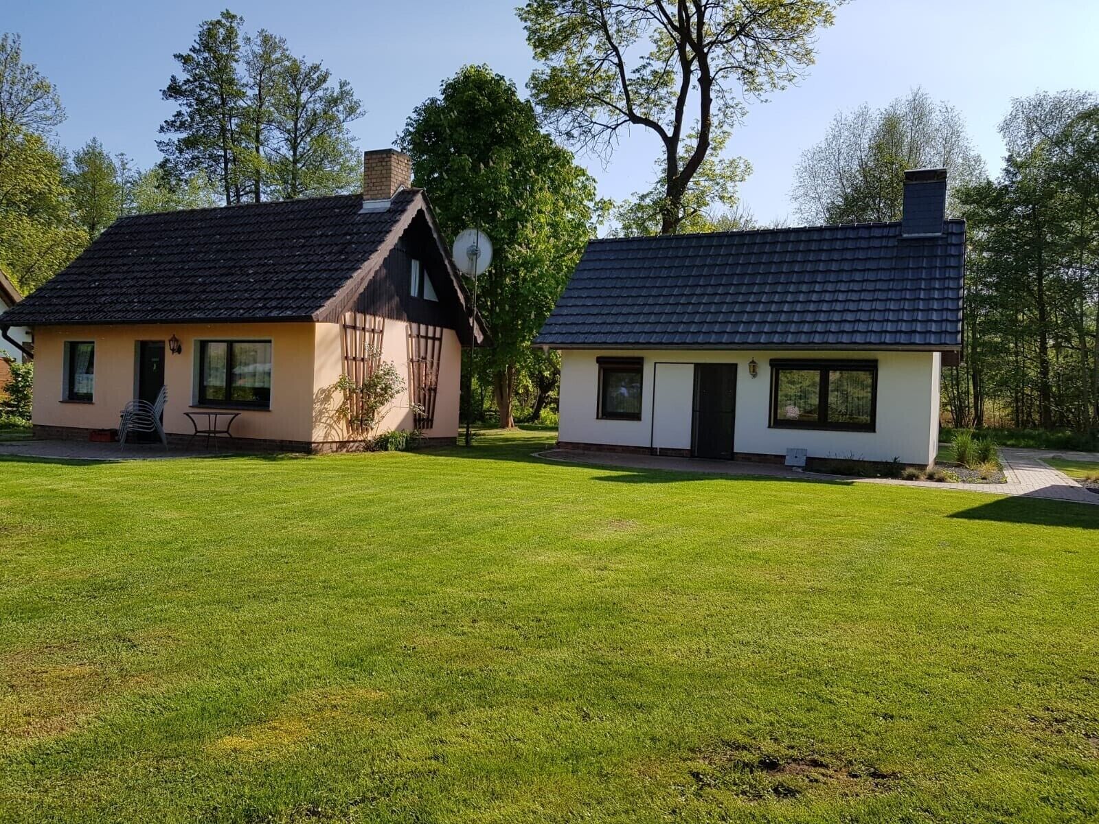 Two houses with distinct architectural styles, one with a sloped roof and the other with a flat roof, both surrounded by a well-maintained lawn.