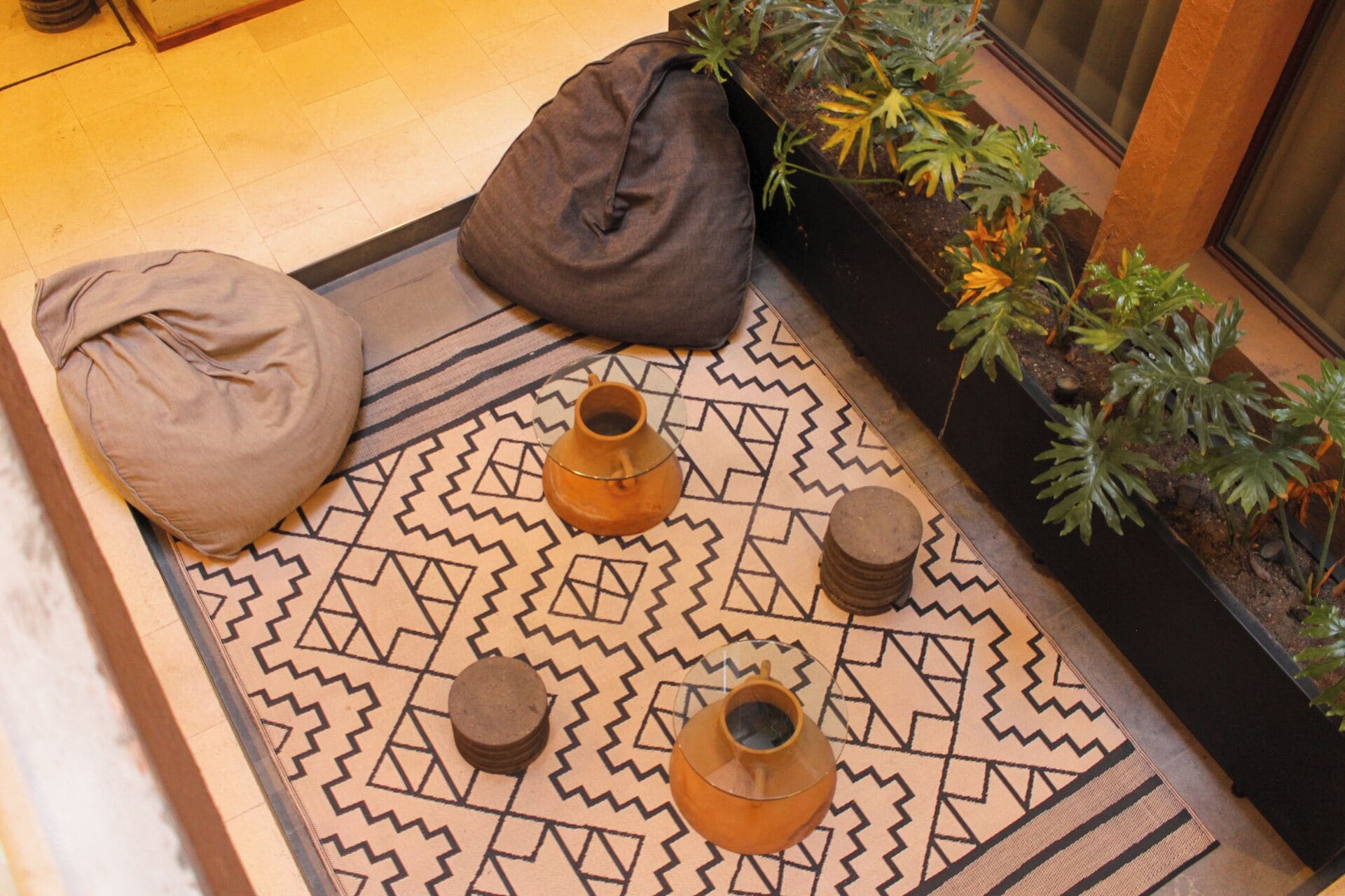 A seating area with a patterned rug, two bean bags, and three small vases.