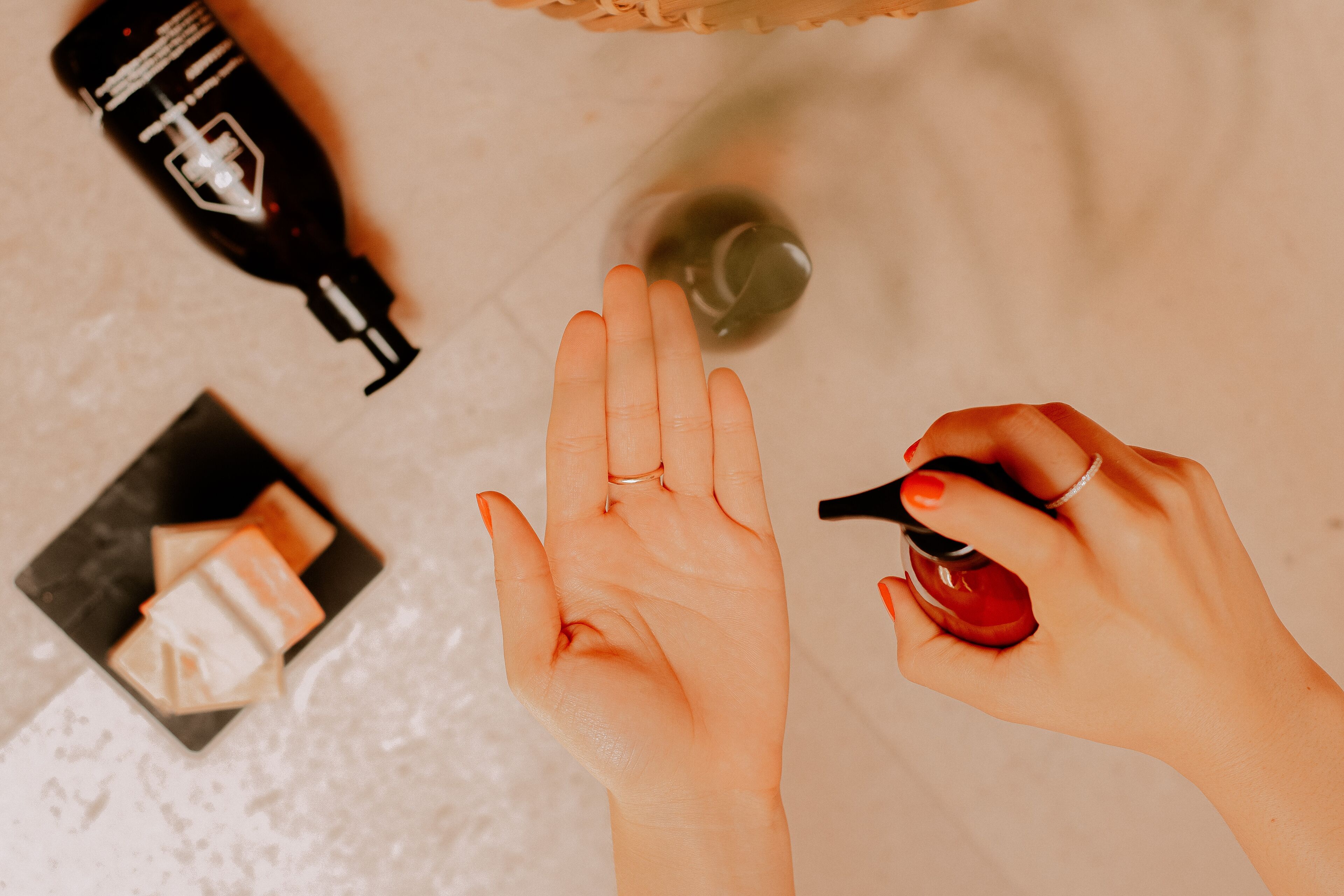 A hand applying a liquid product to the palm, with a bottle and a box of soap visible.