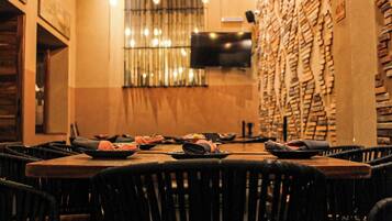 A restaurant with a long table set for multiple guests, chairs around the table, and a wall with a unique brick pattern.