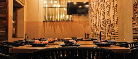 A restaurant with a long table set for multiple guests, chairs around the table, and a wall with a unique brick pattern.