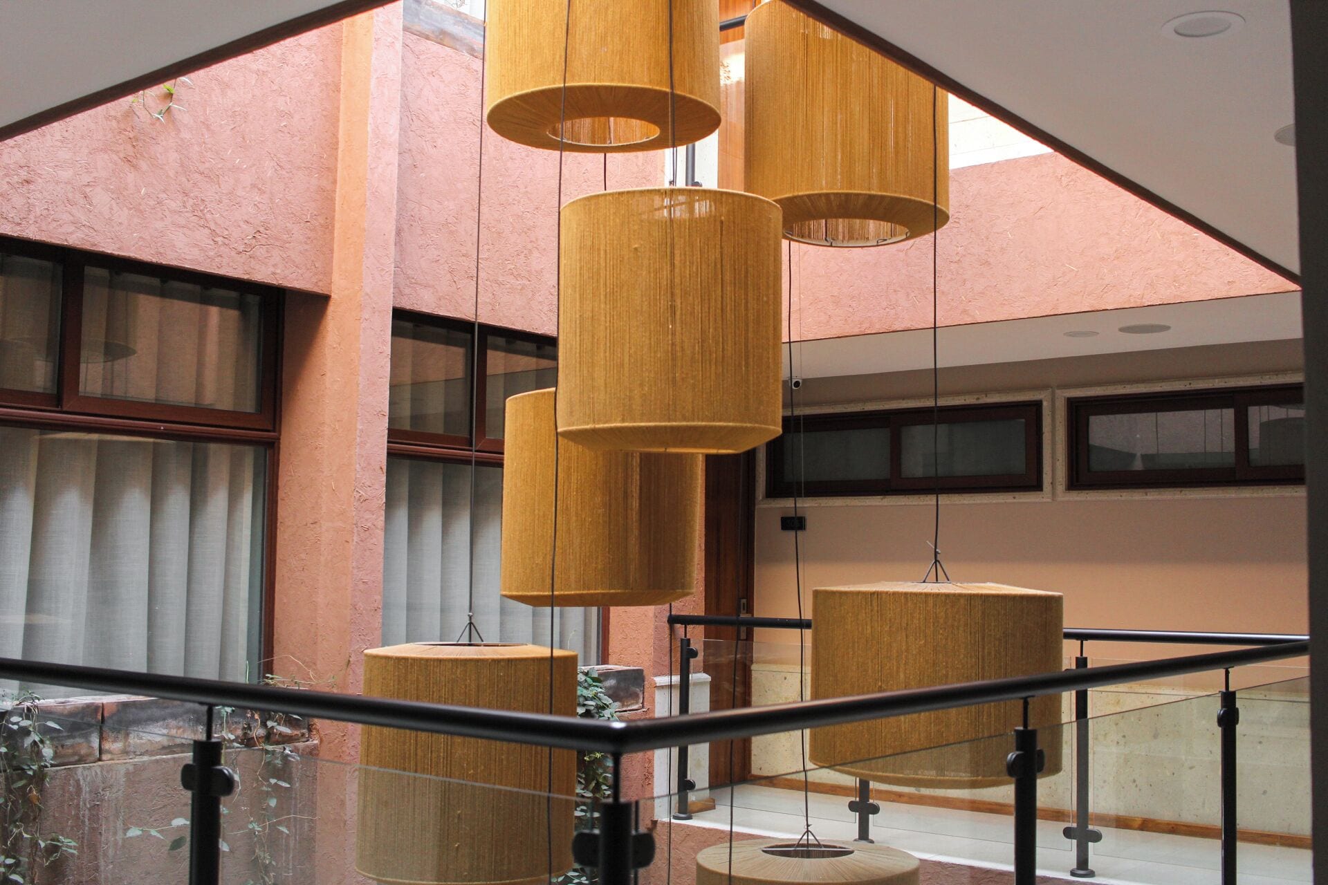 A modern interior with a staircase, large windows, and hanging wooden lamps.