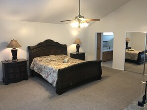 A bedroom with a bed, two bedside tables, a ceiling fan, a mirror, and a view into the adjacent room. - Quail Run 4,000 Sq.Ft Largest and Most Beautiful Cabin On The Mountain (Pine Mountain Club)