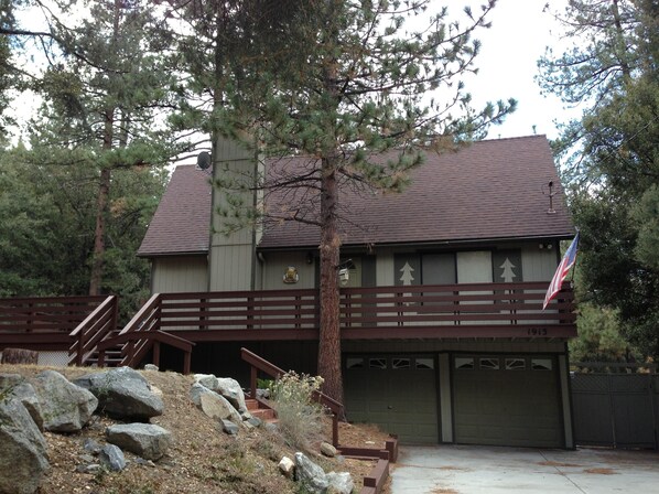 A two-story house with a brown roof, a flag, and a garage. - Quail Run 4,000 Sq.Ft Largest and Most Beautiful Cabin On The Mountain (Pine Mountain Club)