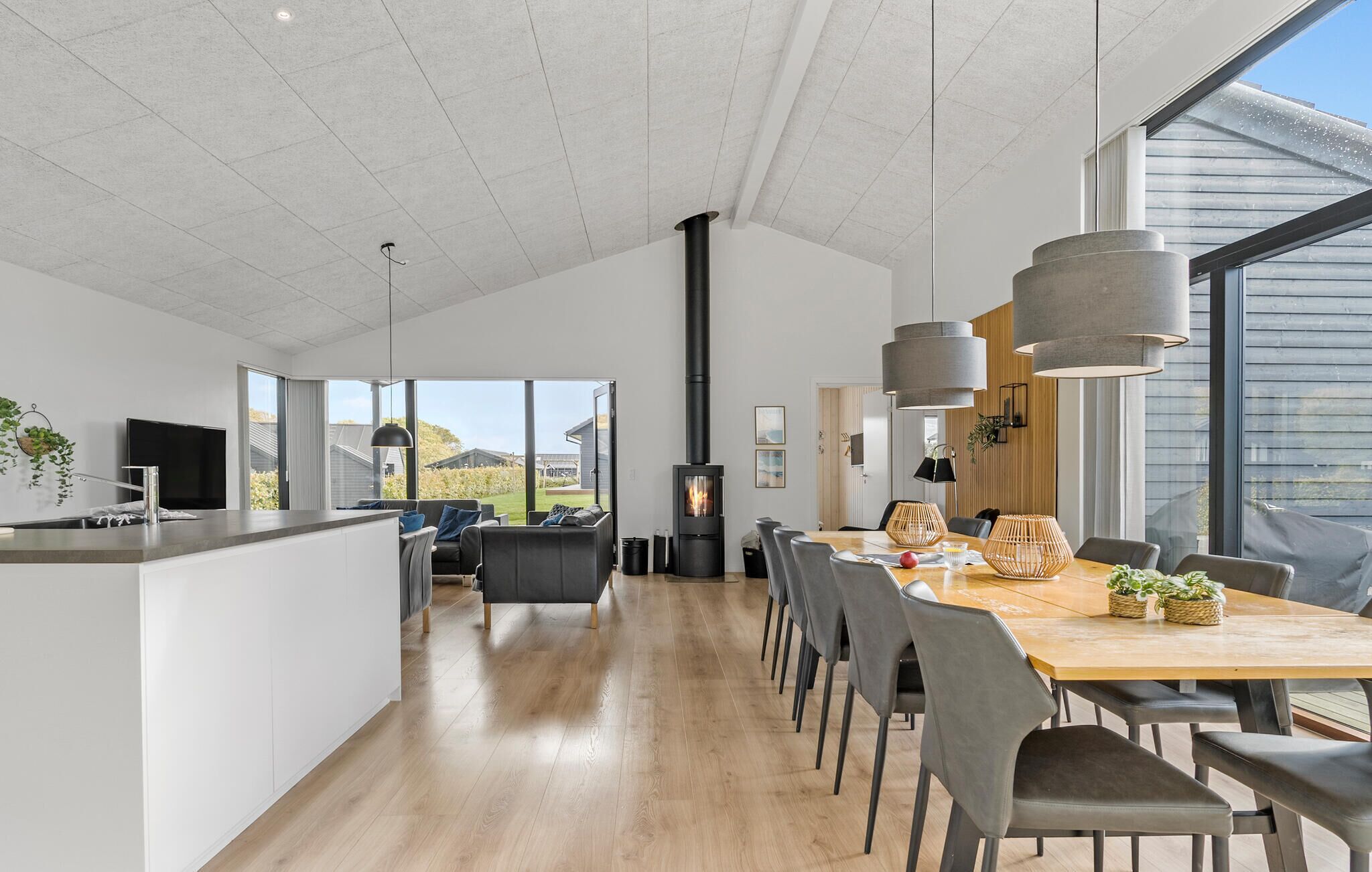 A modern kitchen with a central island, a dining area with a wooden table and chairs, and a large window providing a view of the outdoors.