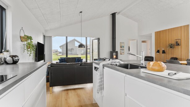 A modern kitchen with a central island, a built-in stove, and a large window offering a view of the outdoors. - 4 bedroom cozy home in Haderslev (Haderslev)