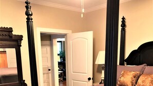 A four-poster bed with a headboard, a bedside table, and a lamp. - Hughes Street House! (Nacogdoches)