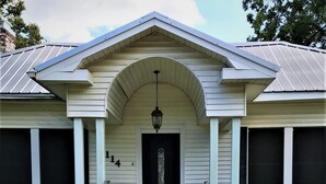 A house with a front porch, a black door, and a number "14" on the wall. - Hughes Street House! (Nacogdoches)