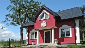 A red house with a dark roof, white trim, and a central door.