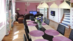 A dining area with a long table, purple placemats, and a vase of flowers.