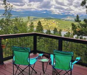 Relax on the deck with a serene view of the surrounding landscape and a tranquil body of water in the distance.