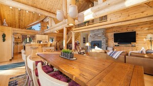 Un interior espacioso de madera con una gran mesa de comedor, una chimenea y un televisor.