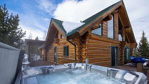Una cabaña de troncos con un jacuzzi en la parte delantera.