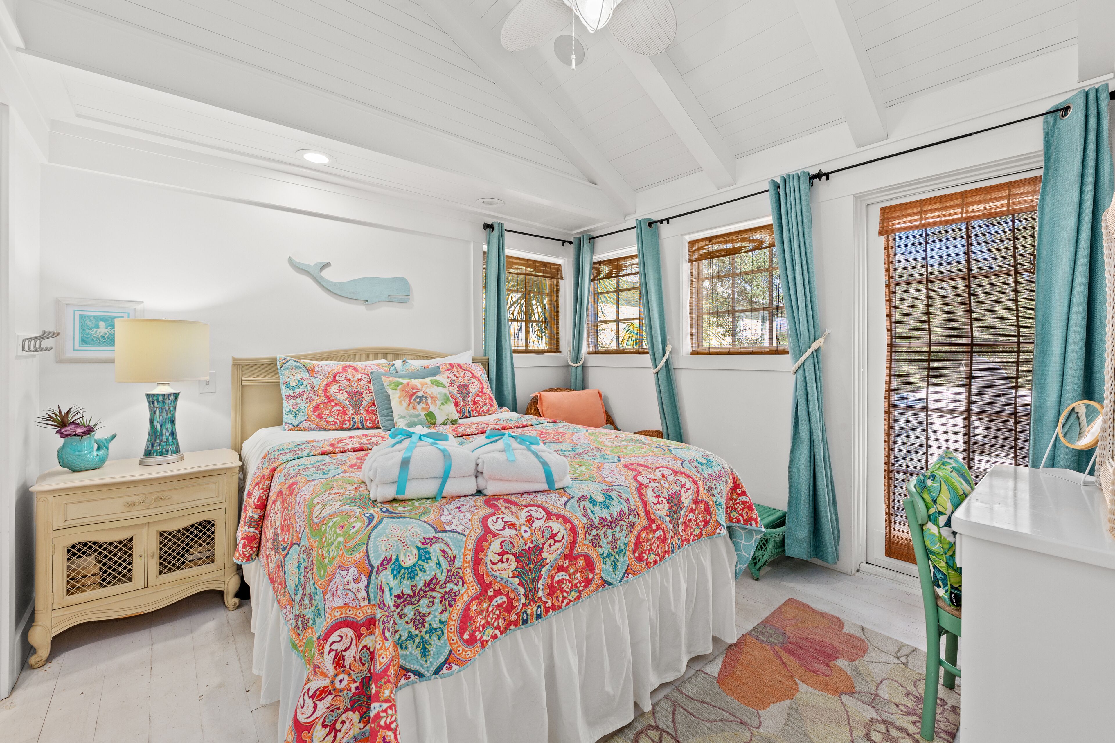 A bedroom with a bed, nightstand, dresser, and a window with curtains.
