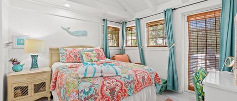 A bedroom with a bed, nightstand, dresser, and a window with curtains.