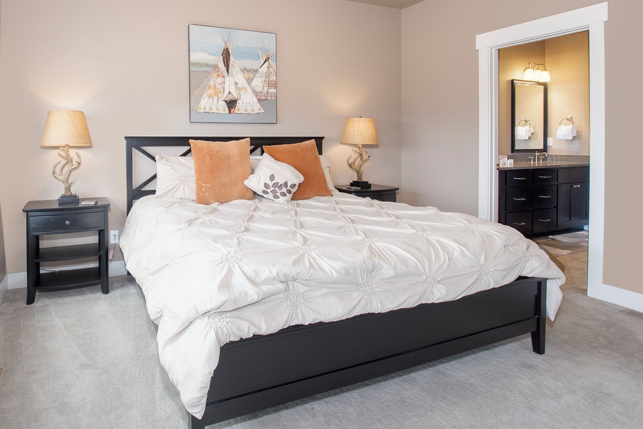Une chambre à coucher avec un grand lit, deux tables de chevet avec des lampes, une commode et un miroir.