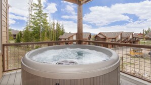 Una vasca idromassaggio su un molo di legno con vista su una zona residenziale e alberi.