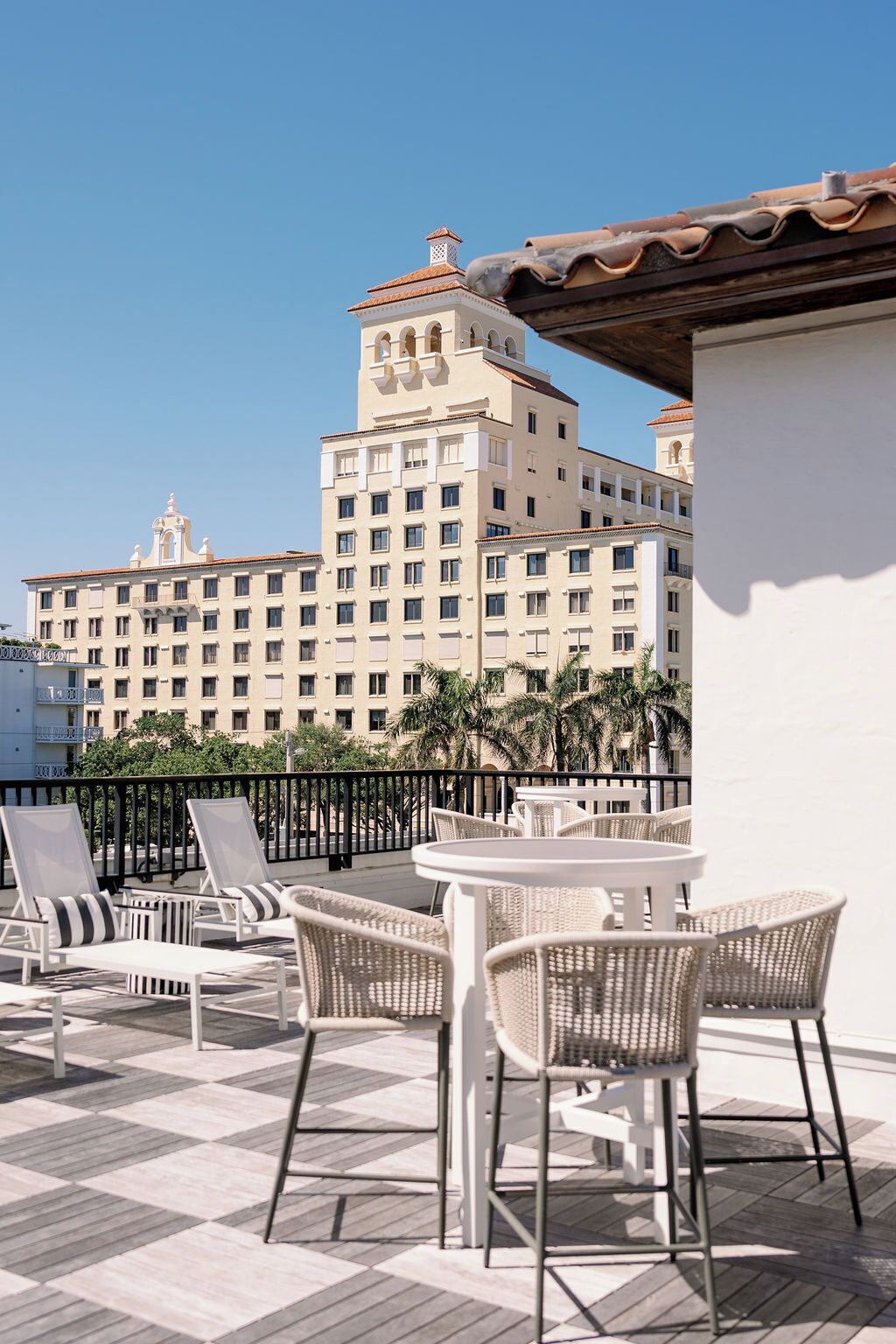 A rooftop terrace with outdoor seating and a view of a large hotel building.