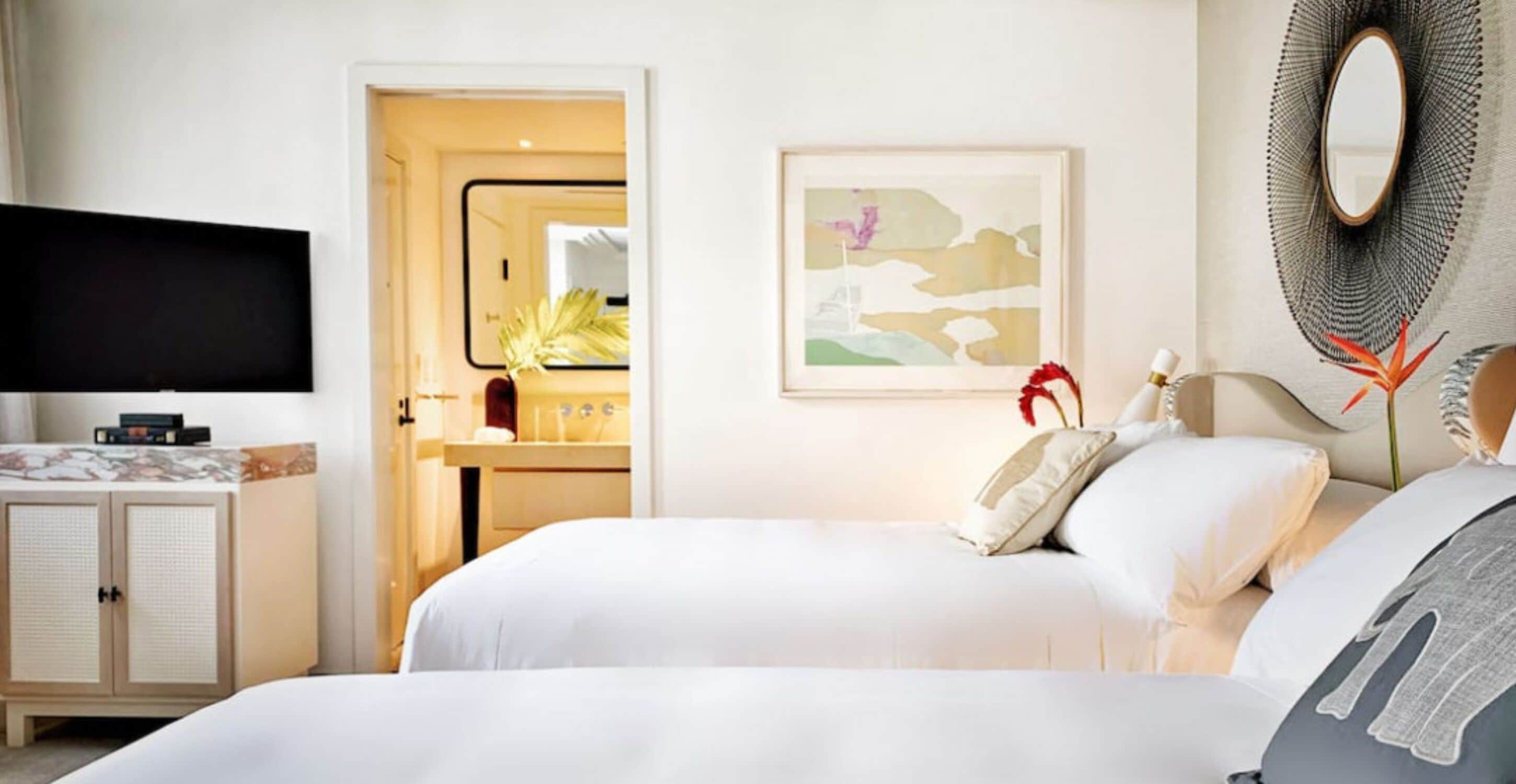 A hotel room with a bed, a TV, a cabinet, a bathroom, and a painting on the wall.