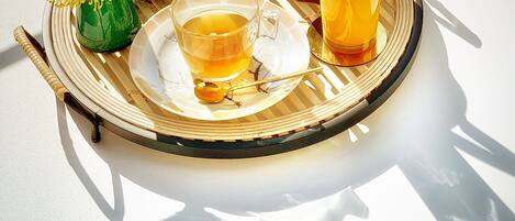 A round table with a tray holding a teapot, a glass of orange juice, a cup of tea, and a pastry.