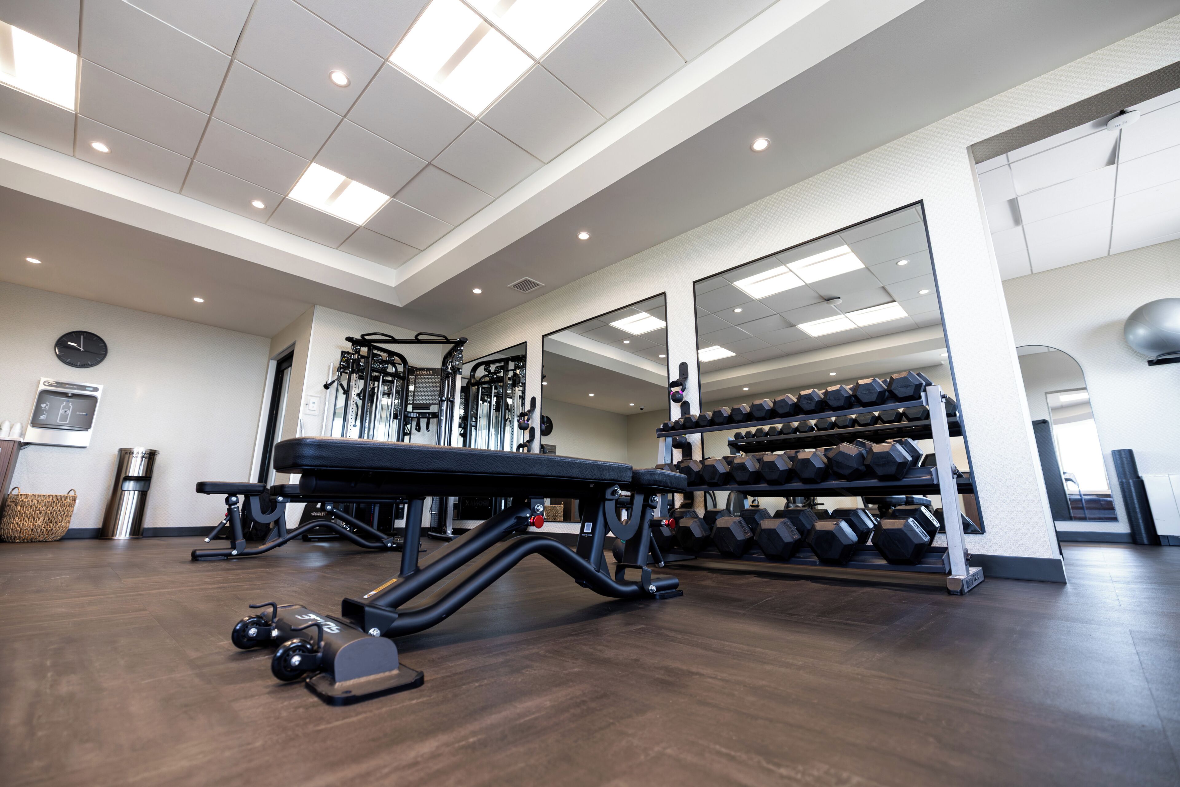 A gym with exercise equipment, a bench, and a rack of dumbbells.