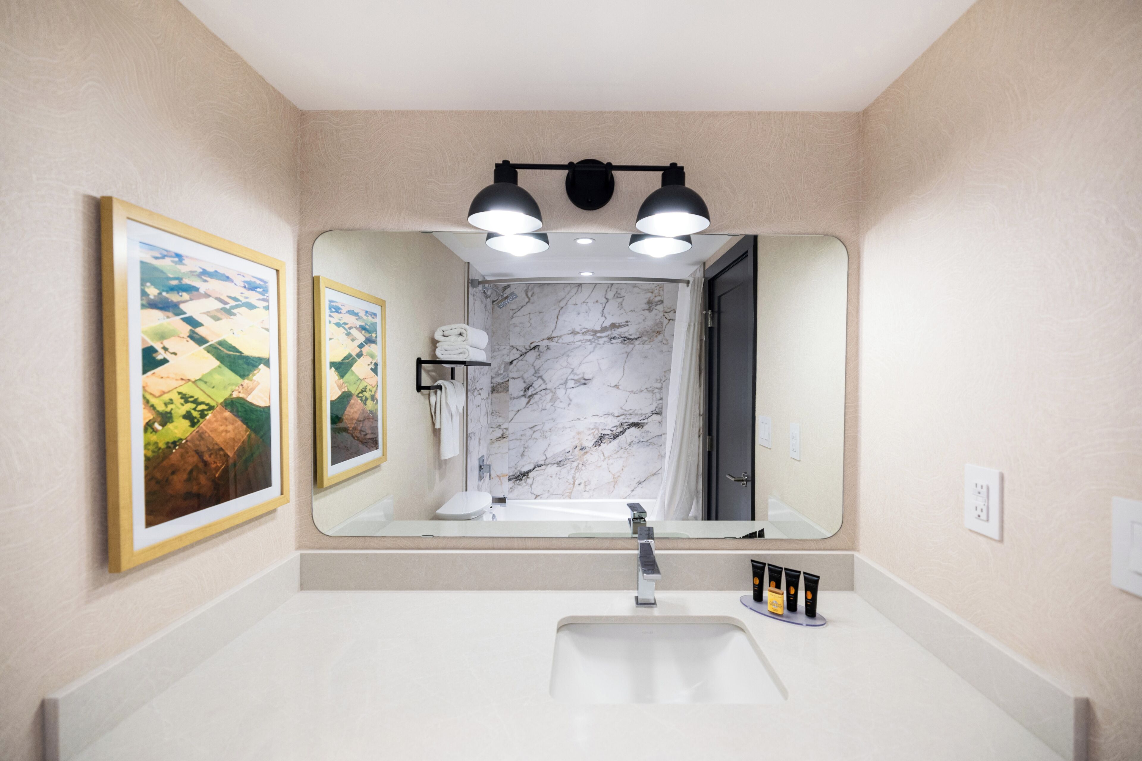 A modern bathroom with a large mirror, a sink, and a shower.