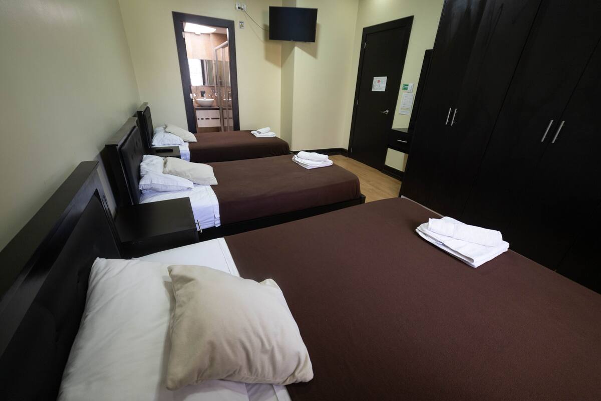A hotel room with two beds, a TV mounted on the wall, and a wardrobe.
