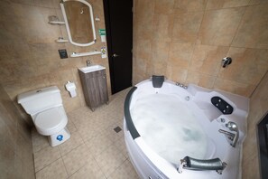 A bathroom with a toilet, sink, and a large bathtub.