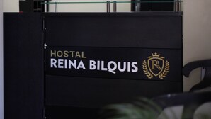 A reception desk with the logo "Hostal Reina Bilquis" and a coat of arms. - Reina Bilquis (Quito)