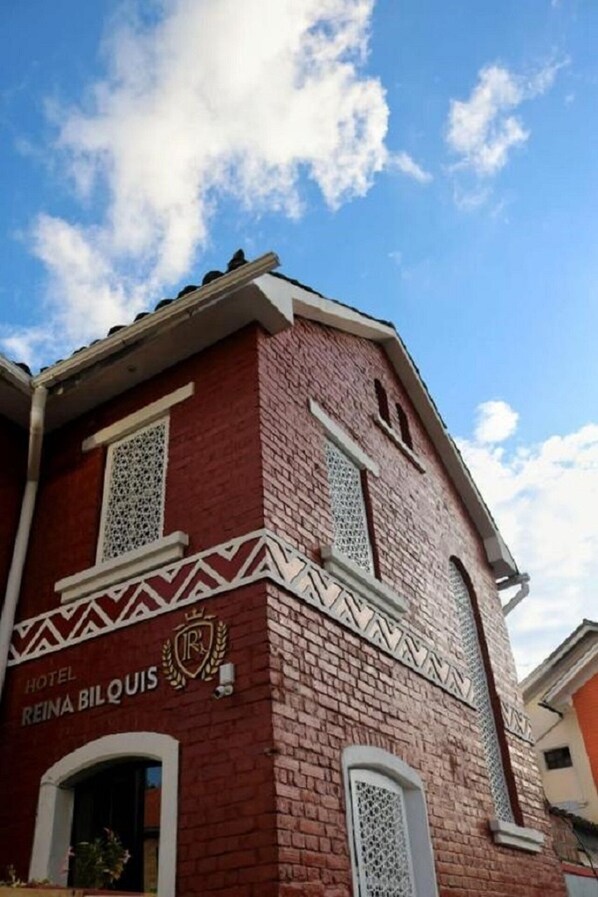 A hotel named "REINA BILQUIS" with a red brick facade and decorative white patterns.