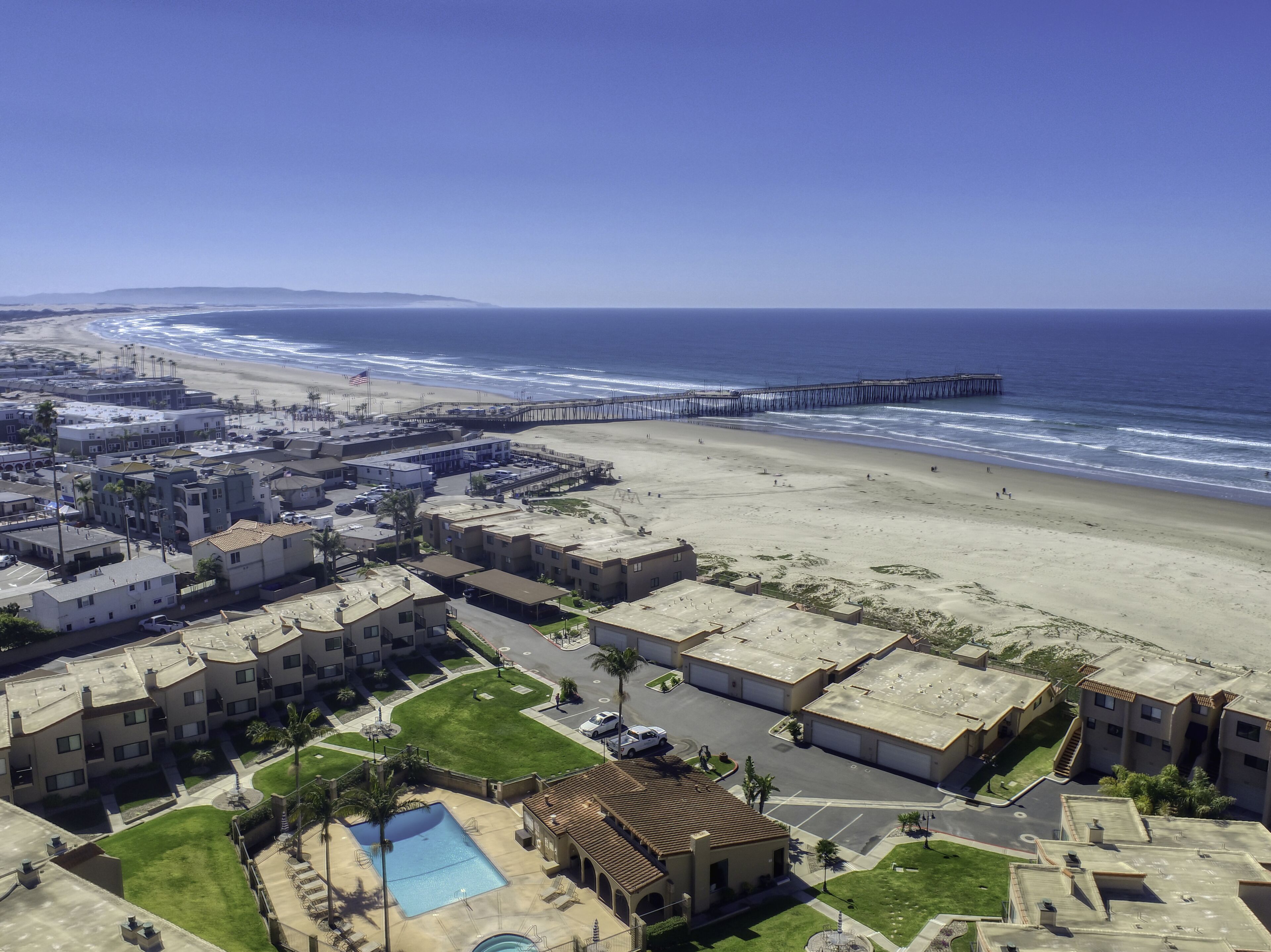 A coastal hotel with a pool, beach access, and a pier.