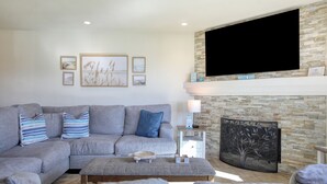 A modern living room with a grey sectional sofa, a coffee table, and a fireplace with a stone accent wall. - Pismo Shores Paradise #119 - 50yds to beach access (Pismo Beach)