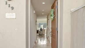 A hallway with a door, a wall-mounted sign, and a light fixture. - Pismo Shores Paradise #119 - 50yds to beach access (Pismo Beach)