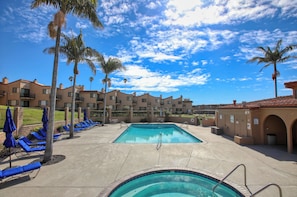 Relax by the resort pool surrounded by palm trees and lounge chairs.