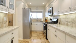 A modern kitchen with white cabinetry, a stainless steel refrigerator, a built-in oven, and a microwave. - Pismo Shores Paradise #119 - 50yds to beach access (Pismo Beach)