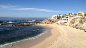 Une plage dotée d’une digue rocheuse, d’un rivage sablonneux et d’immeubles avec des balcons donnant sur la mer.