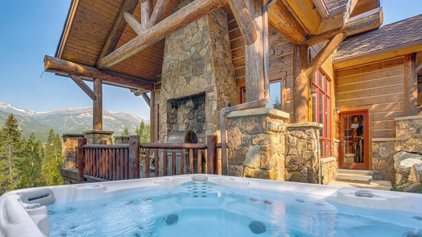A hot tub with a stone fireplace, wooden beams, and a mountain view. - Hilltop Breck Home: Hot Tub, Views & Walk to Town (Breckenridge)