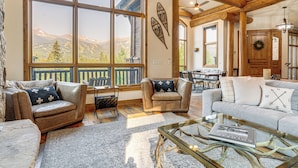 A spacious living area with large windows, a fireplace, and a dining area. - Hilltop Breck Home: Hot Tub, Views & Walk to Town (Breckenridge)