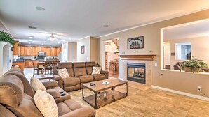 A spacious living room with a brown leather sofa, a coffee table, and a fireplace.